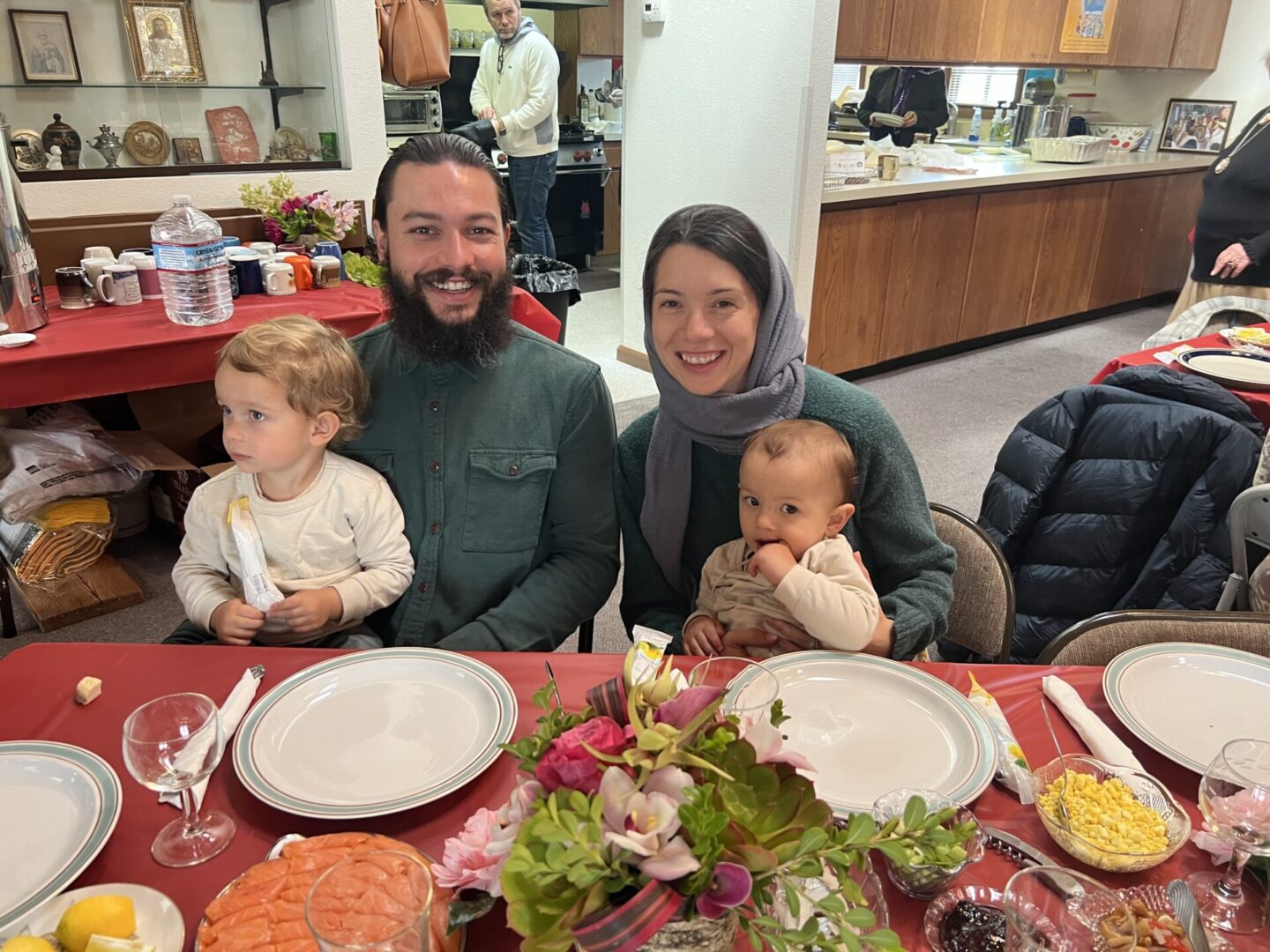 A family sitting at the table with plates of food.