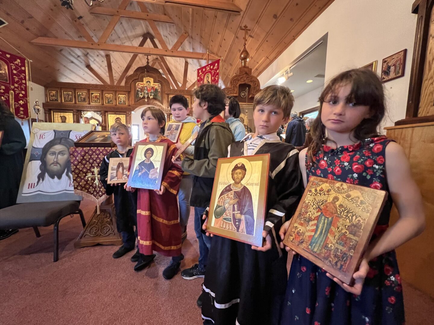 A group of children holding up paintings in front of a wall.