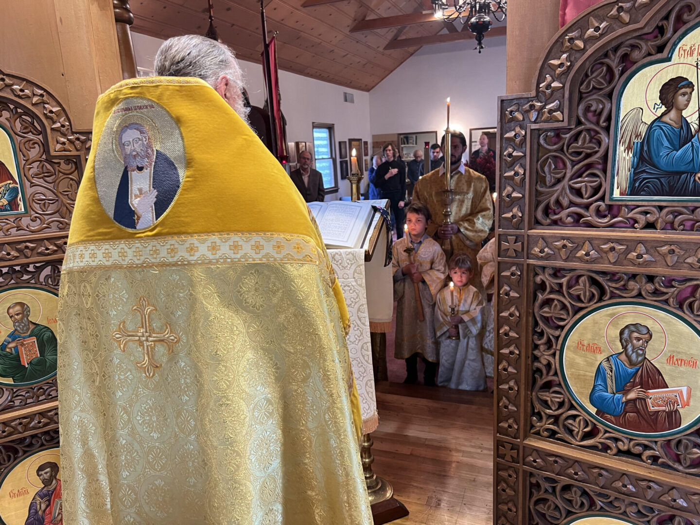 A priest is standing in front of people.