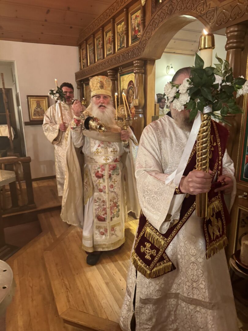 A priest and two men in white robes